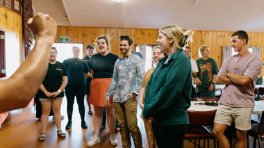 A group of travellers listening to a member of the Māori tribe talk about Māori customs and protocols.