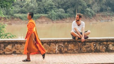 A Buddhist walking along the Nam Khan River in Luang Prabang, Laos