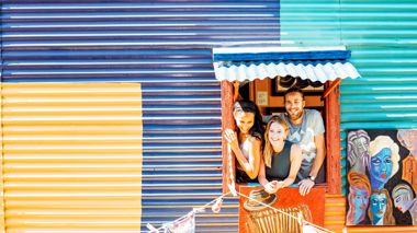 Travellers leaning out of the window of a colourful building in La Boca, Buenos Aires, Argentina