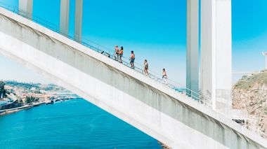 Travellers walking over Arrábida Bridge in Porto, Portugal