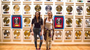 Two Travelers Standing By Record Wall At Country Music Hall of Fame In Nashville, USA