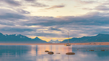 A landscape view of a colourful sunset over a lake with a boat in Puerto Natales, Patagonia