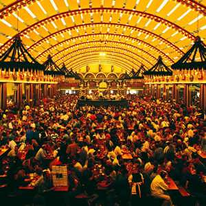 Packed Oktoberfest beer hall tent with ornate vaulted ceiling and thousands of revellers at long wooden tables in Munich Germany - Contiki Oktoberfest Tour