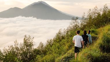 Three travellers climbing up Mt Batur at Sunrise overlooking the island in Ubud, Indonesia