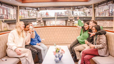 Travellers enjoying a drink together on the Evening Canal Cruise in Amsterdam, Netherlands