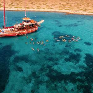 Contiki travellers swimming and snorkelling in the stunning turquoise waters of the Greek Islands from a traditional wooden gulet boat on a Greek island hopping Tour