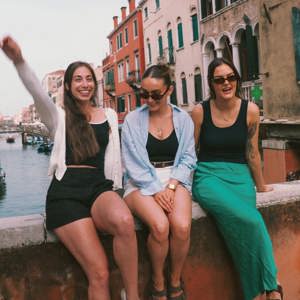 Contiki travellers relaxing on a bridge overlooking a canal in Venice, Italy, on the Vienna to Rome Trail Tour