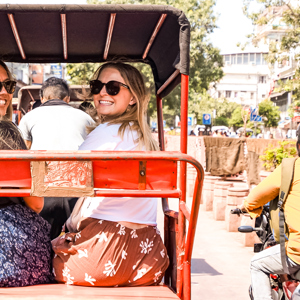 Two travellers sitting in a rickshaw on a busy road in India