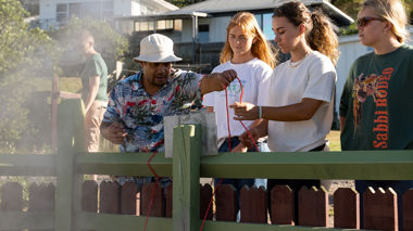 Three travellers learning traditions with a member of the Ngāti Whakaue tribe in Rotorua, New Zealand