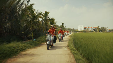 Vintage Vespas carry tourists through lush rice fields, Hoi An, Vietnam