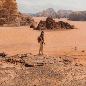 Female traveller on a sandstone rock overlooking the dramatic desert landscape of Wadi Rum Valley of the Moon Jordan - Contiki Jordan Tour
