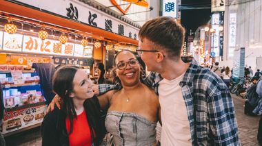 Three Travellers with Arms Around Each Other in Street of Osaka, Japan