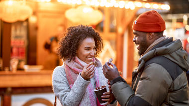 Two travellers enjoying food from a Christmas stall in Paris, France