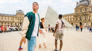 Four travellers exploring Paris together, outside the Louvre in France