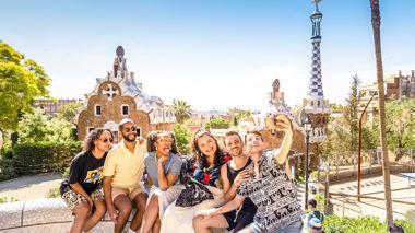 Travellers sitting on a wall taking a selfie in Barcelona, Spain