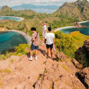 Young travellers on the rocky summit of Padar Island overlooking the iconic tri-bay coastline of Komodo National Park Indonesia - Contiki Indonesia Island Hopping Tour