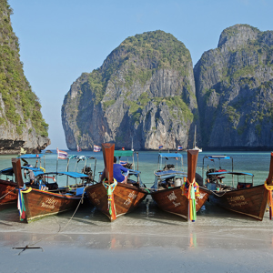 Four boats sitting on the edge of a beach in Thailand