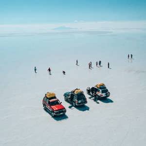 4WD vehicles cross the endless white expanse of Bolivia's Salar de Uyuni as travellers stop to explore