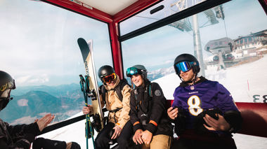 Four travellers in a gondola wearing ski equiptment and carrying skis in Hopfgarten im Brixental, Austria