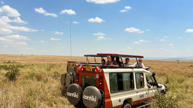 Travellers Looking out of Safari Vehicle with Lion Resting Beside, Maasai Mara, Kenya