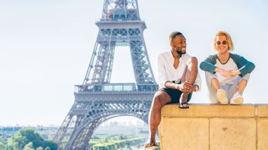 Travellers sitting in front of the Eiffel Tower in Paris, France