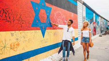 Travellers walking down the Berlin wall looking at the art in Berlin, Germany