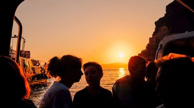 Travellers on a boat at sunset during the included transfer from the port in Athens, Greece