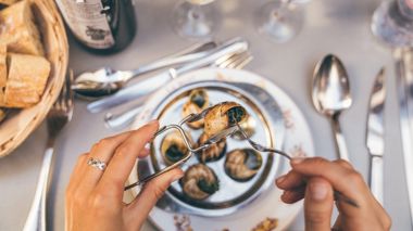 Traveller eating snails during Christmas dinner in Montmartre in Paris, France.