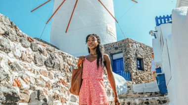 Traveller walking past the windmills in Mykonos, Greece.