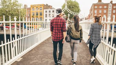Travellers walking over Ha'penny bridge in Dublin, Ireland