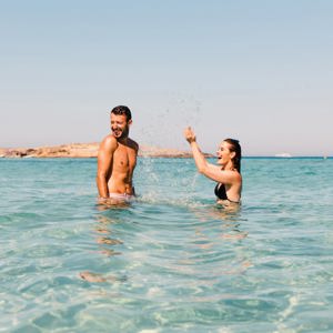 Two young travellers laughing and splashing in crystal clear turquoise waters off the Spanish coast - Contiki Ibiza & Mallorca Island Hopping Tour