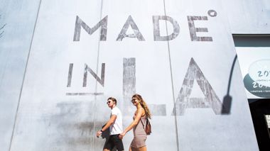 Wall with Made in LA sign and Travellers Walking past, USA
