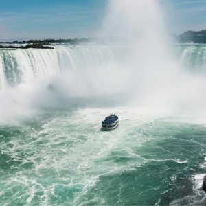 Boat sails through the mist beneath Niagara Falls on Contiki's Canada: Toronto, Niagara & Quebec Tour, experiencing one of Canada's most iconic natural wonders