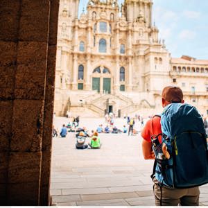 Hiker with backpack arriving at the Cathedral of Santiago de Compostela and Plaza del Obradoiro at the end of the Camino de Santiago Spain - Contiki Hiking Camino Tour