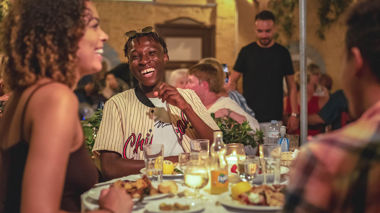 Travellers laughing whilst enjoying a traditional Greek meal in Athens, Greece