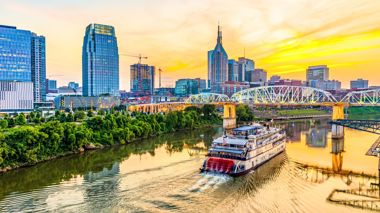 Boat Cruising the Cumberland River at Night against Skyline of Nashville, USA