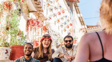 Three travellers sitting on steps surrounded by decorations and flowers in Cusco,Peru
