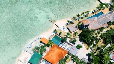 Aerial shot over the beach and houses of Moalboal, Philippines