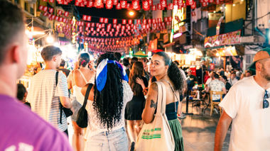 Traveller walking on Khao San road, looking back at camera, Bangkok, Thailand