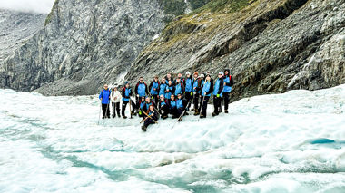 Big group of travellers stood at the edge of a glacier, Franz Josef, New Zealand