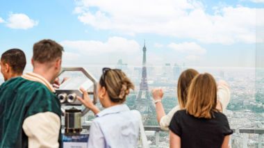 Travellers looking at the Eiffel Tower through binoculars in Paris, France