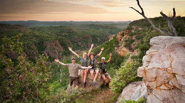 Travellers sat on a rock at the viewpoint over a valley, Kruger National Park, South Africa