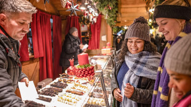 Travellers buying sweet treats from a chocolate stand in a Christmas Market in Frankfurt, Germany