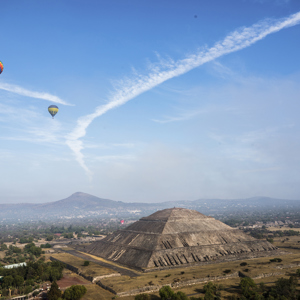 A landscape view of the Pyramind of the Sun, with hot air balloons floating in the sky, in Teotihuacan, Mexico