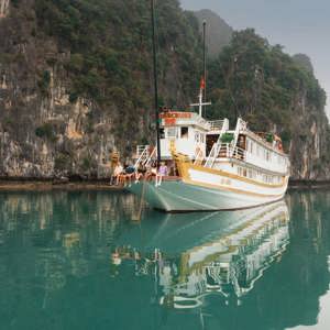 Contiki travellers relaxing aboard an overnight cruise through Ha Long Bay, Vietnam, surrounded by towering limestone karsts on the Ultimate South East Asia Tour