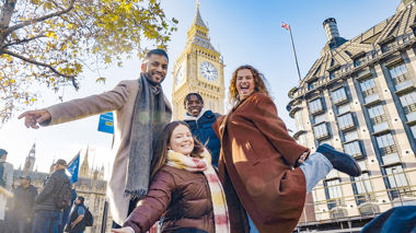 Four travellers posing for a picture in front of Big Ben in London, England