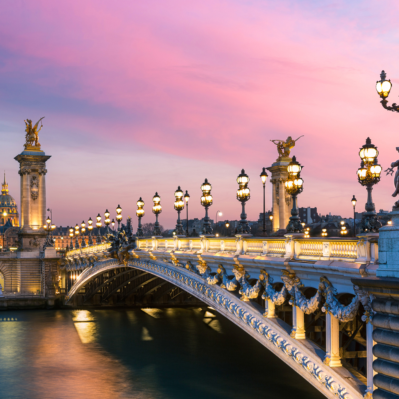 Pont Alexandre III bridge at sunset from the riverbank in Paris, France