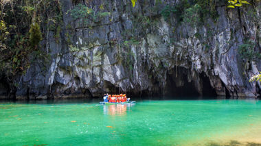 Travellers with Guide Cruising through Clear Blue Water on Small Boat towards Underground Cave in Cliff, Puerto Princesa, Philippines