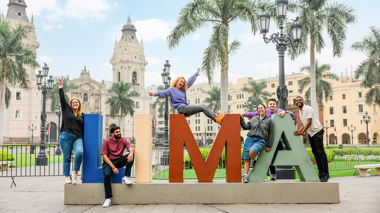 Travellers posing on Lima letters sign, Peru