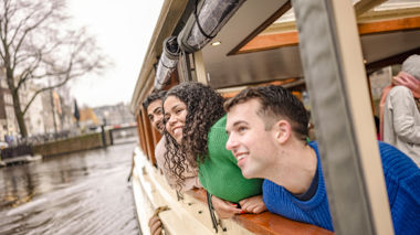 Traveller smiling as he looks onto the canals on a cruise in Amsterdam, Netherlands